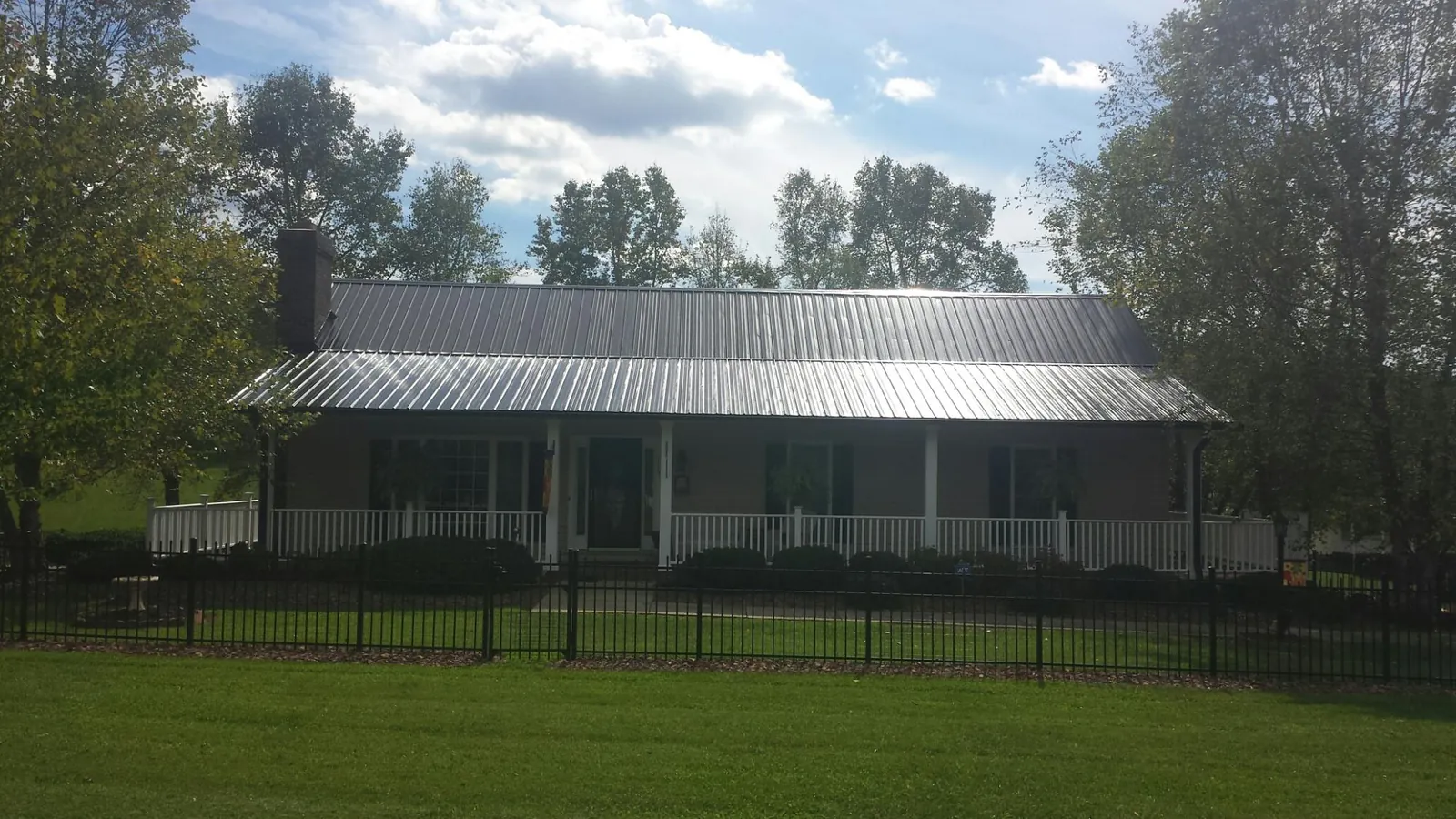 Gray metal roof on a brick ranch with a full width front porch — Gutter Guard Installation work by our crew in Bancroft
